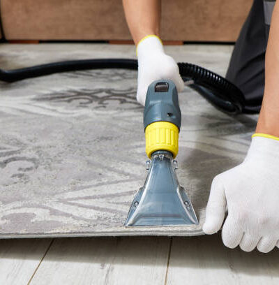 Professional carpet cleaning with vacuum cleaner in a spacious and luxurious living room interior. Room is elegantly decorated with modern furniture and soft, plush carpet.